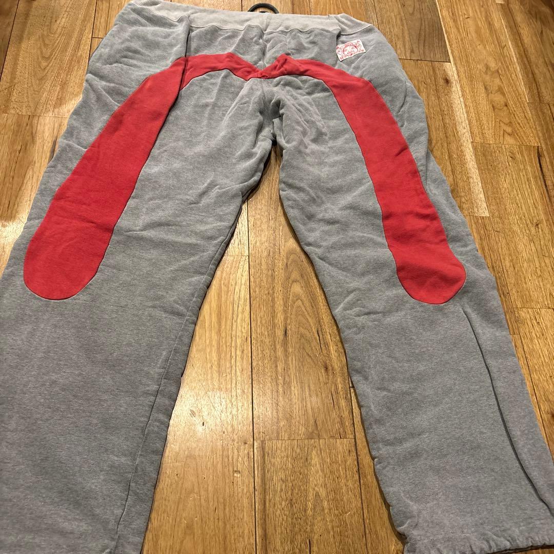 グレー スウェットパンツ 赤いパッチ 金色ロゴ