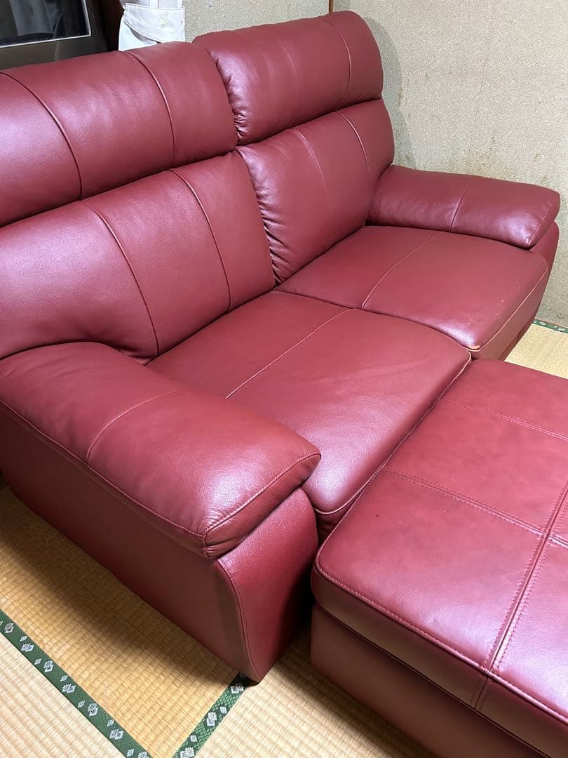 赤い合成皮革の2人掛けソファとオットマン