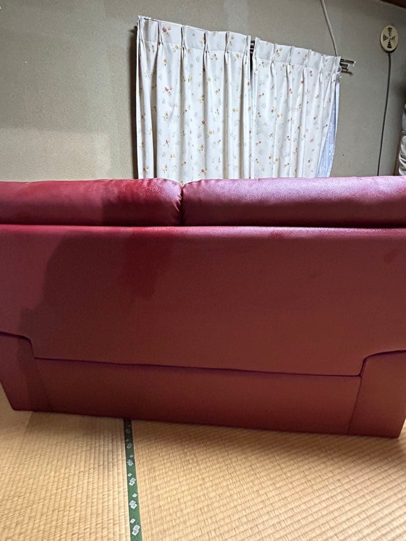 赤い合成皮革の2人掛けソファとオットマン