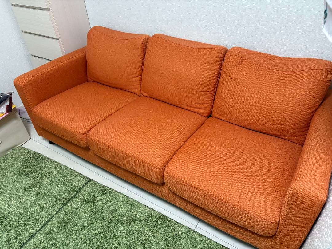 オレンジ色の3人掛けソファ